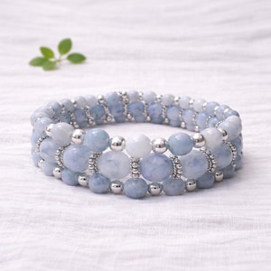 May include: A set of three ceramic mugs with a speckled, matte finish. The mugs are in shades of cream, light gray, and dark gray. Each mug has a simple, minimalist design and a rounded handle.