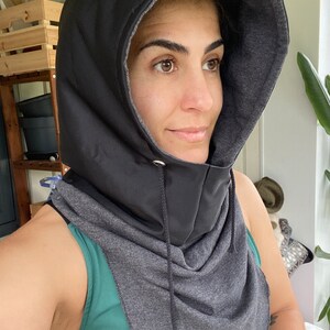Puede incluir: Un cuello de cuello negro con capucha y forro de vell&oacute;n gris. El cuello de cuello tiene un cierre de cord&oacute;n y est&aacute; hecho de una tela suave y c&oacute;moda.