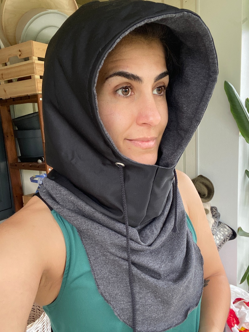 Puede incluir: Un cuello de cuello negro con capucha y forro de vell&oacute;n gris. El cuello de cuello tiene un cierre de cord&oacute;n y est&aacute; hecho de una tela suave y c&oacute;moda.