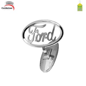 Peut inclure: Un emblème Ford chromé brillant, avec l'inscription Ford dans un cadre ovale. L'emblème est monté sur une base incurvée de couleur argentée. L'image est sur fond blanc, soulignant la surface réfléchissante de l'emblème.