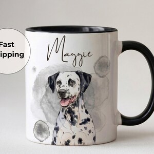 May include: White ceramic mug with a black handle and rim, featuring a watercolour illustration of a Dalmatian dog. The dog's name, "Maggie", is written above the dog in cursive. The mug has a watercolour background.