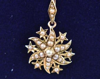 Könnte beinhalten: Ein goldener Anhänger mit Sternenmotiv, verziert mit kleinen, runden, cremefarbenen Saatperlen. Das zentrale Element ist eine größere Perle, umgeben von strahlenden Spitzen und Sternformen, alles in Gold gefasst, mit einer rautenförmigen Öse.