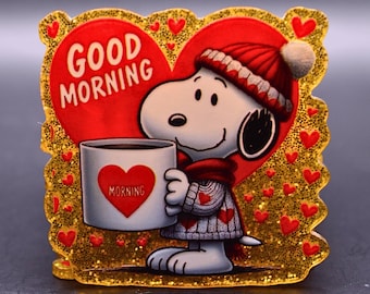 Può includere: Una targa decorativa quadrata con finitura glitterata dorata raffigurante un cane dei cartoni animati con berretto e maglione di lana rossa, che tiene una tazza bianca con un cuore rosso e la scritta MORNING, su un grande cuore rosso con GOOD MORNING.