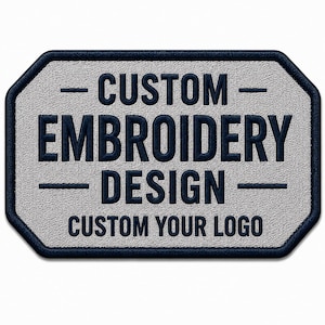 Op de afbeelding: Een rechthoekige patch met afgeronde hoeken, een lichtgrijze textuurachtergrond en een donkerblauwe rand. De tekst CUSTOM EMBROIDERY DESIGN is geborduurd in donkerblauw, met de tekst CUSTOM YOUR LOGO eronder.