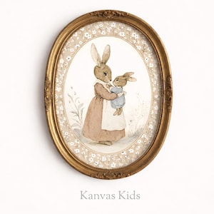May include: An oval, gold-framed print featuring a mother rabbit holding a baby rabbit. The rabbits are depicted in soft watercolor tones, wearing clothing. The background has a floral pattern and the text "Kanvas Kids" is at the bottom.