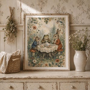May include: A framed print depicts a whimsical tea party scene with a mouse, frog, and rabbit gathered around a table. The illustration features a forest setting with colorful flowers and a vintage aesthetic. The characters are dressed in human clothing.