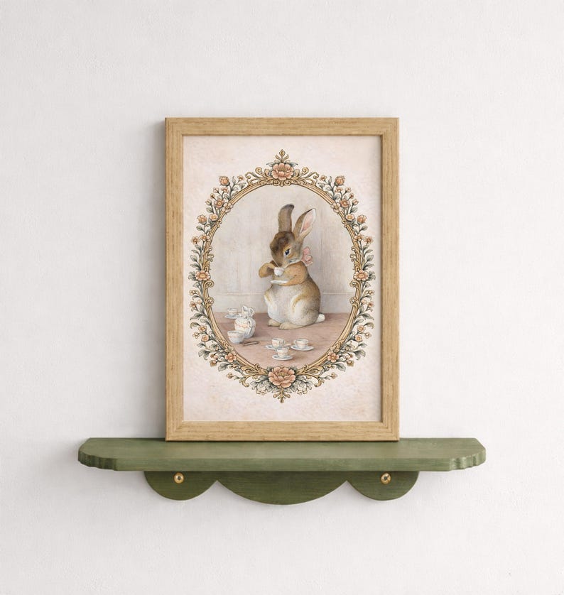 May include: A framed print featuring a watercolor illustration of a rabbit enjoying tea. The artwork is set within an oval floral frame, with a light brown wooden frame. The rabbit is depicted with a pink bow, surrounded by teacups and a small mouse.