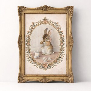 May include: A framed print featuring a watercolor illustration of a rabbit enjoying tea. The rabbit is inside an oval floral frame, surrounded by teacups and a teapot. The ornate gold frame adds a vintage touch to the artwork.