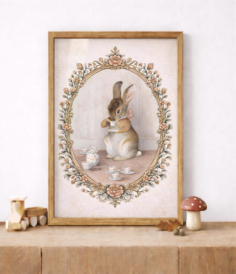 May include: A framed watercolor print depicts a rabbit enjoying tea. The rabbit, wearing a pink bow, is inside an oval floral frame. Teacups and a teapot are on the table. The frame is set against a light pink background.