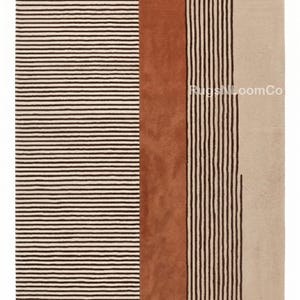 May include: A rectangular area rug featuring a cream background with a pattern of dark brown horizontal stripes on the left, a solid burnt orange vertical band in the centre, and dark brown vertical stripes on the right. The text RugsNLoomCo is visible.