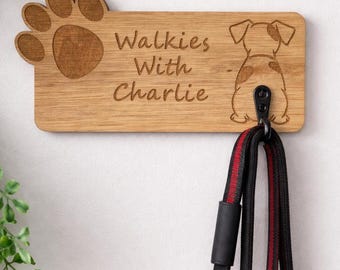 Puede incluir: Soporte de correa para perros de madera con una huella de pata y una ilustración de perro. El letrero dice "Walkies With Charlie". Una correa negra y roja cuelga del gancho. Un artículo encantador y práctico para dueños de perros.
