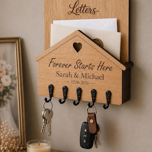 Puede incluir: Un organizador de correo y llavero de pared de madera marr&oacute;n claro. La secci&oacute;n superior est&aacute; grabada con la palabra Letters. La secci&oacute;n inferior en forma de casa presenta un recorte de coraz&oacute;n, el texto Forever Starts Here, Sarah & Michael y 12.06.2026.