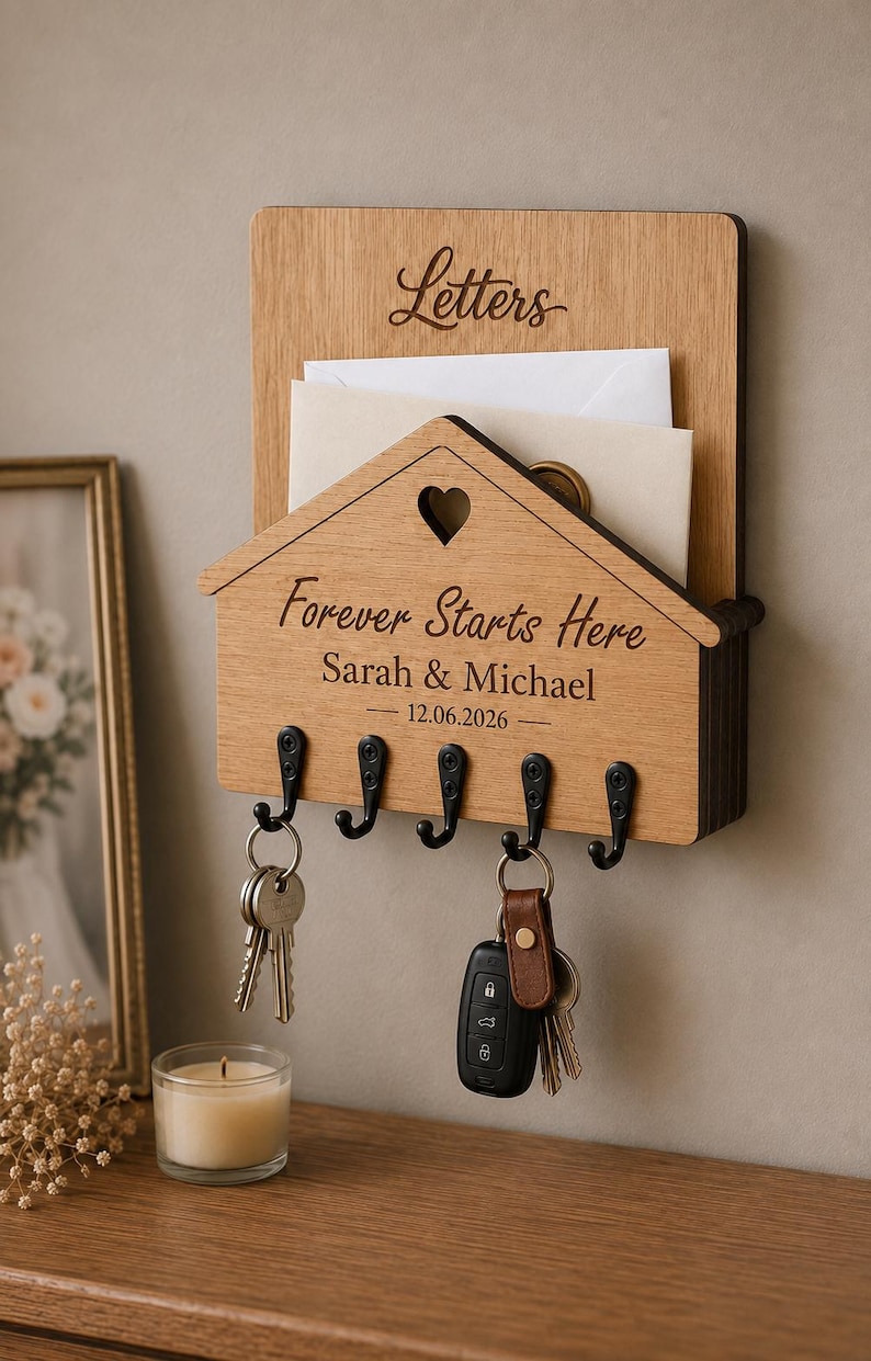Puede incluir: Un organizador de correo y llavero de pared de madera marr&oacute;n claro. La secci&oacute;n superior est&aacute; grabada con la palabra Letters. La secci&oacute;n inferior en forma de casa presenta un recorte de coraz&oacute;n, el texto Forever Starts Here, Sarah & Michael y 12.06.2026.