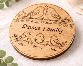 Puede incluir: Una placa redonda de madera con ilustraciones grabadas con láser de pájaros sobre ramas. El texto dice "Mum", "Dad", "Davies Family", "Oliver", "Emmy" y "Jack". Dos pájaros grandes están arriba con un corazón y tres pequeños abajo.
