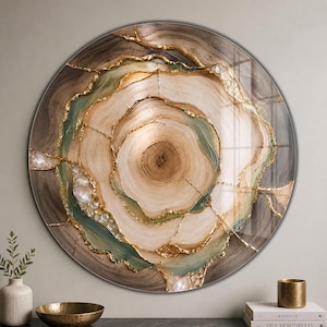 Può includere: Un'opera d'arte murale circolare che raffigura una sezione trasversale di un tronco d'albero con anelli concentrici in tonalità beige, marrone e verde salvia. Il design è arricchito da venature dorate e cristalli trasparenti sotto una finitura lucida.