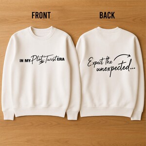 May include: Cream-coloured sweatshirt. The front features the text "IN MY Plot Twist ERA" and the back says "Expect the unexpected...", both in black script. It has a crew neck and long sleeves.