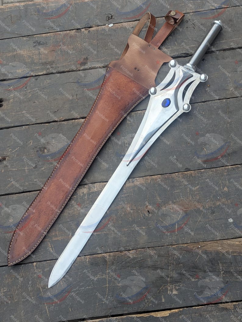 May include: A silver sword with a decorative hilt and a blue gem, next to a brown leather sheath. The sword has a long, pointed blade and a detailed handle with silver accents. The sheath has a strap for carrying.