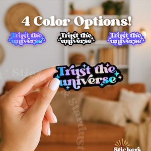 May include: A sticker with the text "Trust the universe" in a gradient of blue, purple, and teal, with star accents. The image shows four color options. The sticker is held by a person.