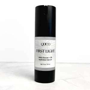 May include: A black cylindrical bottle of "FIRST LIGHT" hydration serum. The label includes the brand name "QDICO" and the text "Beta Glucan + B5 Hydration Serum". The bottle contains 1 fl oz / 30 ml of product.