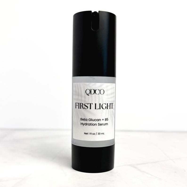 May include: A black cylindrical bottle of "FIRST LIGHT" hydration serum. The label includes the brand name "QDICO" and the text "Beta Glucan + B5 Hydration Serum". The bottle contains 1 fl oz / 30 ml of product.