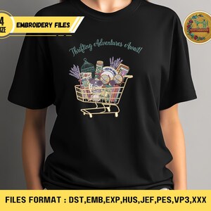 May include: Black t-shirt with a colorful graphic of a shopping cart filled with vintage items. The text "Thrifting Adventures Await!" is above the cart. The shirt also has the text "EMBROIDERY FILES" and "FILES FORMAT : DST, EMB, EXP, HUS, JEF, PES, VP3,XXX".