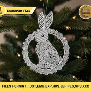 Op de afbeelding: Een wit, ingewikkeld ontworpen konijnenornament met een bloemenkrans, hangend aan een kerstboom. Het ornament heeft de tekst "EMBROIDERY FILES" en "1 SIZE". De afbeelding toont ook de bestandsformaten: DST, EMB, EXP, HUS, JEF, PES, VP3,XXX.