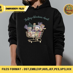 May include: Black hoodie with a graphic of a shopping cart filled with vintage items, lavender, and the text "Thrifting Adventures Await!". Includes "4 SIZE" and "EMBROIDERY FILES" text. The bottom of the image displays "FILES FORMAT : DST, EMB, EXP, HUS, JEF, PES, VP3, XXX".
