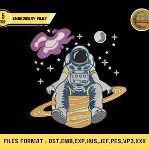 May include: An embroidered design featuring an astronaut seated on a planet with rings, surrounded by stars, a moon, and a purple nebula. The design includes the text "EMBROIDERY FILES" and "5 SIZE". The file formats are listed at the bottom.