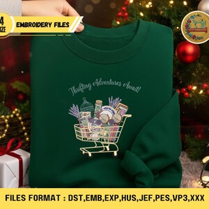 May include: A dark green sweatshirt with an embroidered design of a shopping cart filled with vintage items and lavender. The text "Thrifting Adventures Await!" is above the cart. The image also includes text that says "4 SIZE EMBROIDERY FILES" and "FILES FORMAT : DST, EMB, EXP, HUS, JEF, PES, VP3, XXX".