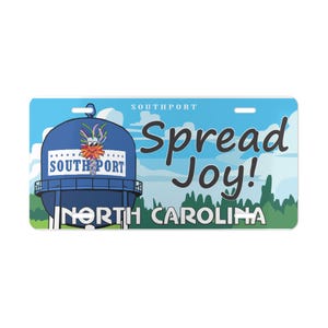 May include: A license plate featuring a blue water tower with the text "Southport" and "North Carolina." The plate has the words "Spread Joy!" in a playful font against a blue sky background.