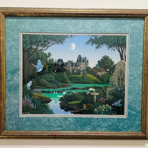 May include: A framed print of a painting depicting a fairytale-like castle nestled in a lush green forest. The castle has a white facade with a gray roof and is surrounded by a pond with a moon reflecting in the water. The painting features a blue sky with white clouds and a moon in the upper right corner. The frame is gold with a teal mat.