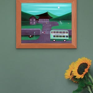 May include: A framed painting depicts a green double-decker bus labeled THE IRISH TIMES driving past a stone wall, a park with figures, and buildings set against rolling green hills under a pale moon in a light blue sky.