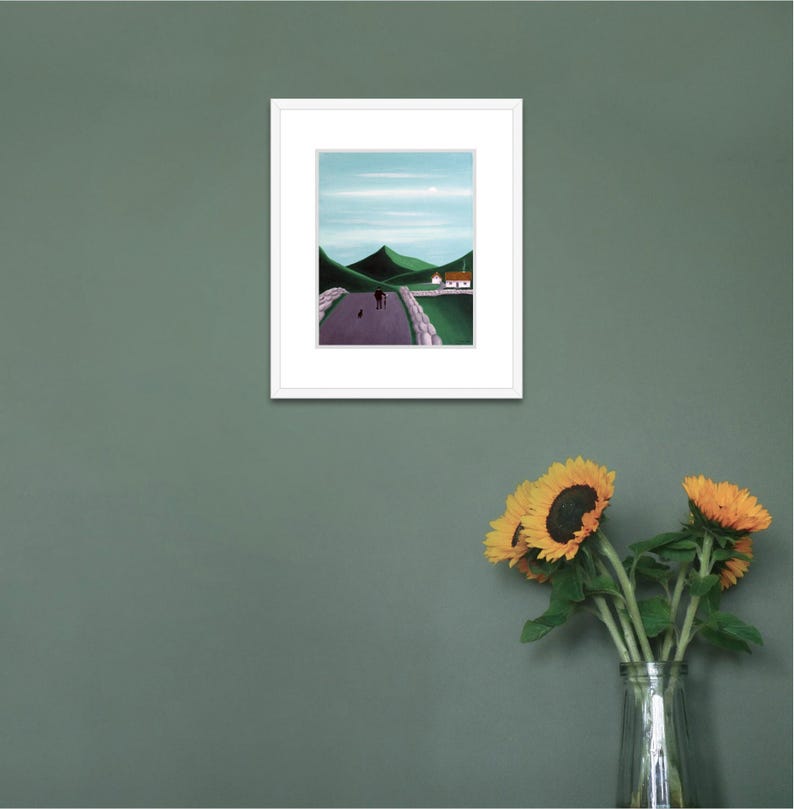 Pode incluir: Uma pintura de paisagem emoldurada apresentando uma estrada roxa que leva a colinas verdes sob um c&eacute;u azul claro. Uma pequena casa branca com telhado vermelho fica perto das colinas. Duas figuras caminham pela estrada com um animal.