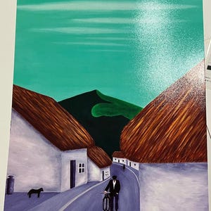 May include: An original painting showing a rural scene with white houses, brown thatched roofs, and a road. A person in a suit walks with a bicycle. A black dog is near a stone container. The sky is teal with a bright spot.