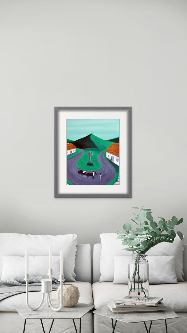 May include: A framed painting depicting a rural landscape with a winding purple road, two white cottages with orange roofs, a central stone cross, and a horse-drawn cart. The background features rolling green hills under a pale sky.