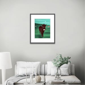 Puede incluir: Una l&aacute;mina de arte enmarcada que muestra un burro de color marr&oacute;n oscuro de pie en un campo verde bajo un cielo verde azulado con una peque&ntilde;a luna blanca y dos edificios blancos distantes. La obra tiene un marco negro fino con paspart&uacute; blanco.