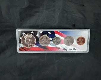 May include: A clear plastic case containing a Birthyear Set of U.S. coins, including a Kennedy half dollar, a quarter, a dime, a nickel, and a penny. The coins are displayed against a backdrop of the American flag.