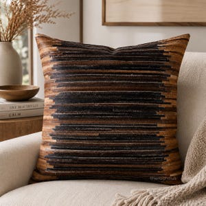 May include: A square throw pillow featuring a horizontal striped pattern in shades of dark brown, black, and tan. The design consists of layered, textured bands that create a dense, linear appearance across the entire surface of the cushion.