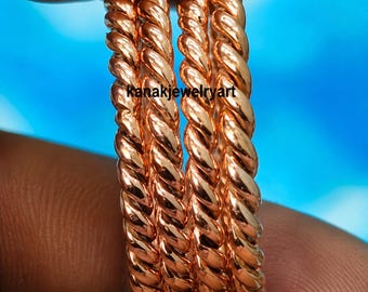 May include: A set of three copper-colored rings with a twisted rope texture. The rings feature a polished, metallic finish and are stacked together. The text "kanakjewelryart" is printed in black across the center of the rings.