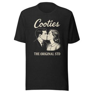May include: Dark gray t-shirt with the text "Cooties" above a black and white illustration of a kissing couple with spots. Below the illustration, the text reads "THE ORIGINAL STD".