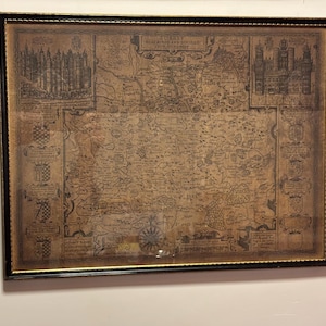 Può includere: Mappa antica incorniciata di una regione, con cartografia e illustrazioni dettagliate. La mappa è in una cornice nera e dorata, che aggiunge eleganza vintage. L'aspetto invecchiato e i dettagli intricati della mappa suggeriscono un significato storico.