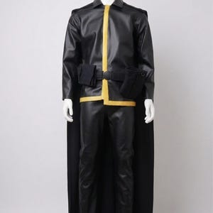 May include: Black faux leather costume with yellow trim, displayed on a mannequin. The outfit includes a jacket, pants, belt with pouches, and a cape. The Zohra Attire logo is visible in the upper left corner.