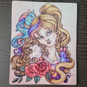 May include: A completed jigsaw puzzle featuring a whimsical illustration of a woman with long, flowing blonde hair and two rabbits. The artwork includes pink roses and colorful accents of blue, purple, and yellow.