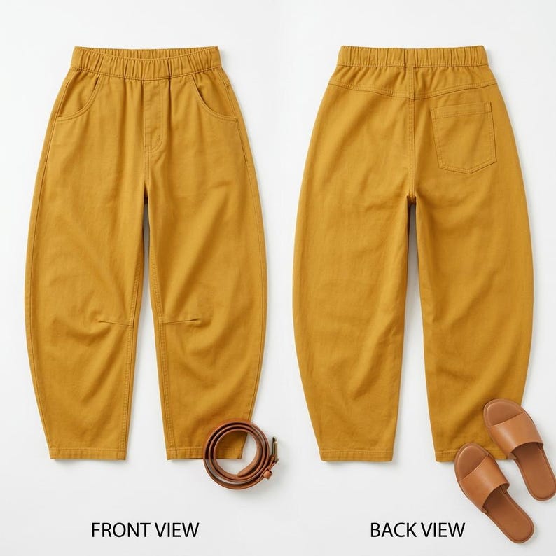 Op de afbeelding: Mosterdkleurige broek met een elastische tailleband, voorzakken en een enkele achterzak. De voorkant toont de broek met een bruine riem, terwijl de achterkant wordt getoond met bruine sandalen. De broek heeft een relaxte pasvorm.