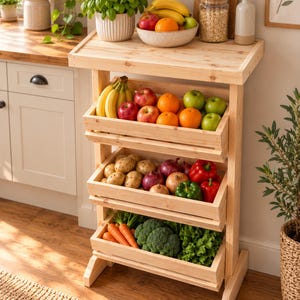 May include: A three-tier wooden produce stand featuring a flat top surface and three open-slatted crates. The top crate holds bananas, apples, and oranges. The middle crate contains potatoes, red onions, and bell peppers. The bottom crate holds carrots, broccoli, and lettuce.