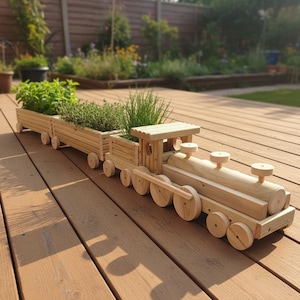 May include: A light-coloured wooden train planter featuring a locomotive engine and two attached cargo cars. The train and cars are filled with green herbs and plants. The structure is constructed from horizontal wooden slats and round wheels.