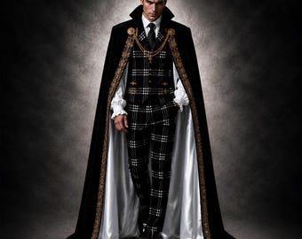 Pode incluir: Uma capa longa de veludo preto com bordados dourados, usada sobre um fato aos quadrados preto e branco com colete e calças. O conjunto inclui uma camisa branca com punhos com folhos, uma gravata preta e um acessório de corrente dourada.