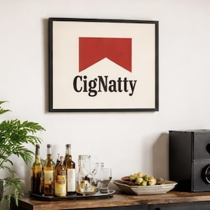 Könnte beinhalten: Ein gerahmter Kunstdruck mit einem rot-weißen Design und dem Wort "CigNatty" in Schwarz. Der Druck hängt über einem Holzschrank mit Flaschen, Gläsern und einem Lautsprecher. Links ist eine grüne Pflanze.