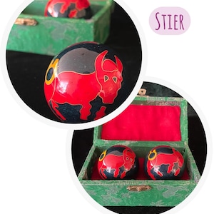 Könnte beinhalten: Eine weiße Keramik-Tasse mit schwarzem Henkel und dem Text "But First, Coffee" in fetter, schwarzer Schrift. Die Tasse steht vor einem verschwommenen Hintergrund, der eine gemütliche Umgebung suggeriert.