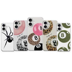 May include: A collection of phone cases with various designs. One case features a black spider, while others showcase pool ball designs, including a pink ball with the number 8, leopard print, and a green ball with the number 8.
